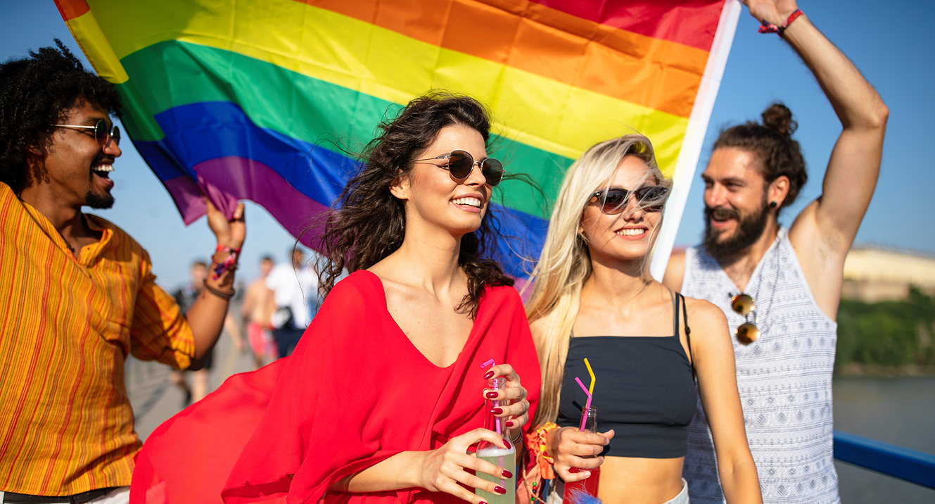 Menschen mit Regenbogenflagge bei Sonnenschein